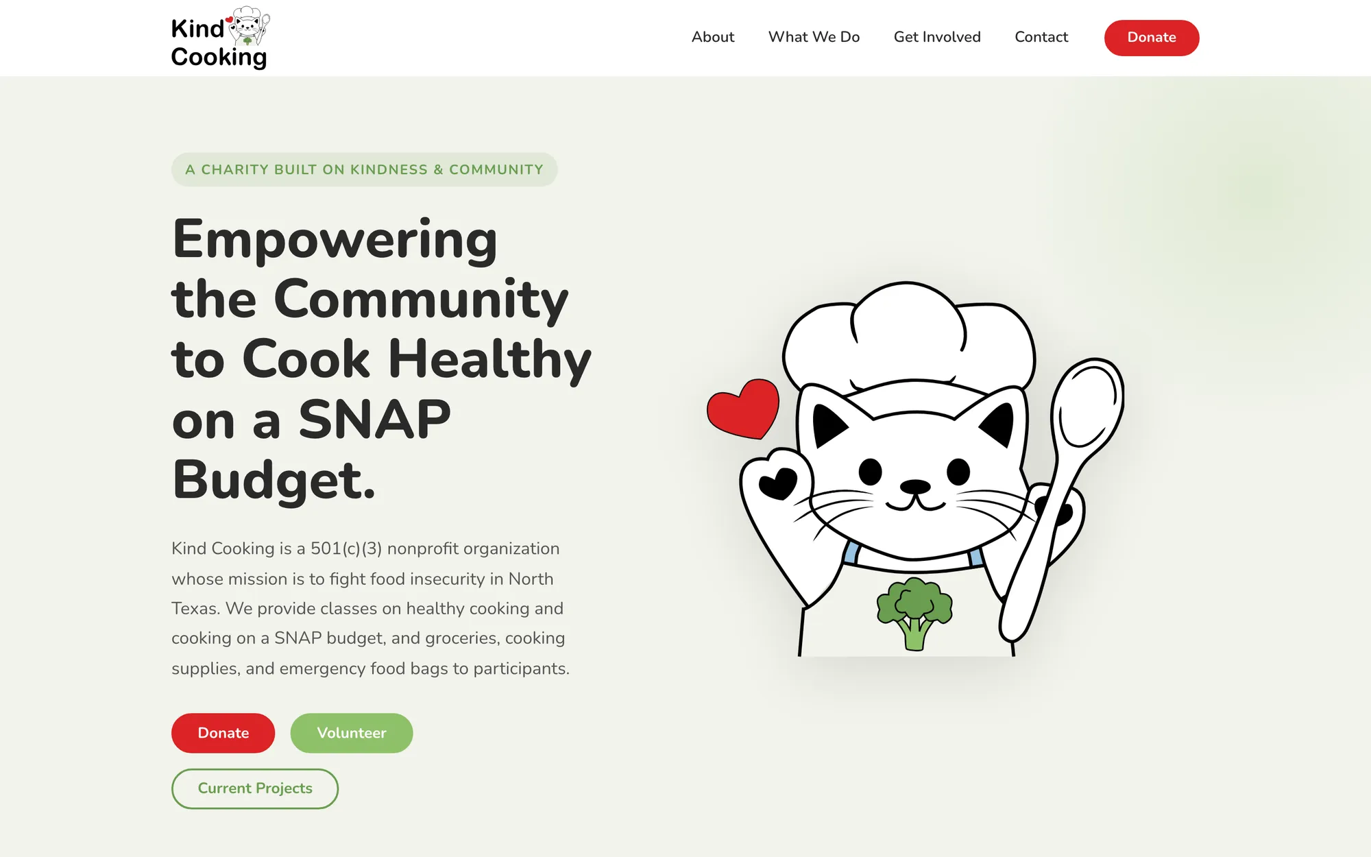 The Kind Cooking homepage. A drawn cat in a chef's hat holding a wooden spoon sits beside the headline 'Empowering the Community to Cook Healthy on a SNAP Budget', with red Donate and green Volunteer buttons below it.